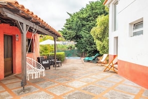 Eine Terrasse mit Hängesessel, Liegestühlen und einem Whirlpool.