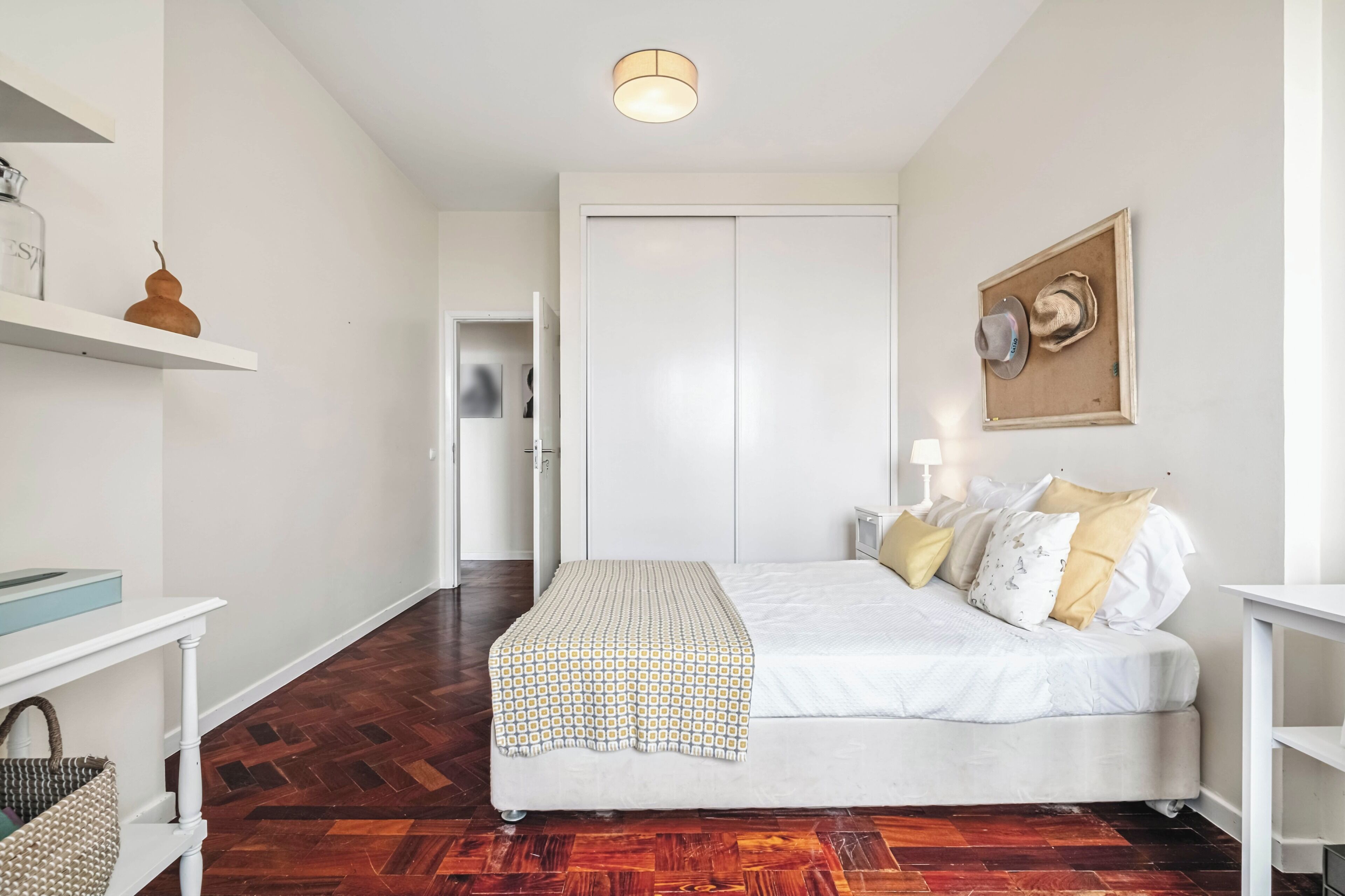 A bedroom with a bed, bedside table, lamp, and a wardrobe.