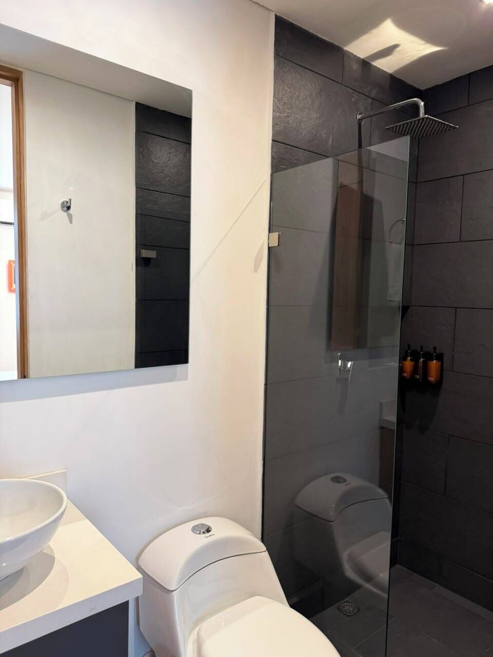 Ein modernes Badezimmer mit einer gläsernen Duschkabine, einer Toilette und einem Waschbecken.