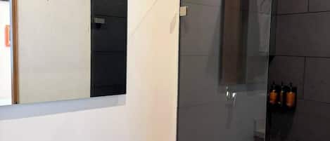 Ein modernes Badezimmer mit einer gläsernen Duschkabine, einer Toilette und einem Waschbecken.