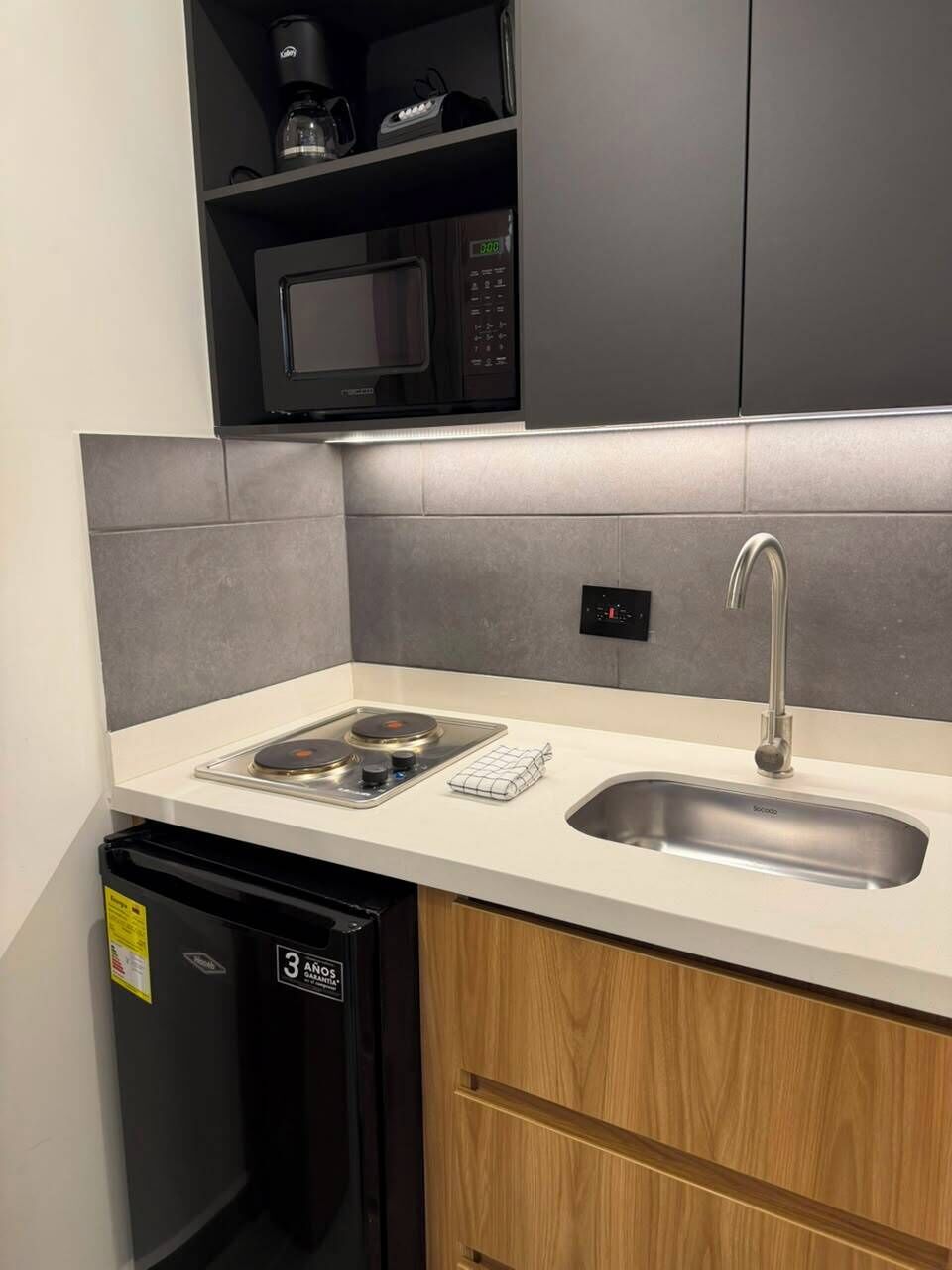 A compact kitchen with a microwave, a built-in oven, a sink, and a dishwasher.