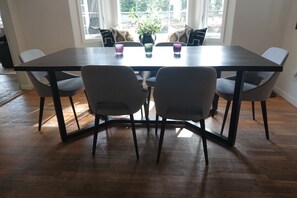 Un comedor con una mesa rectangular, cuatro sillas grises y dos copas pequeñas sobre la mesa.