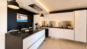 Eine moderne Küche mit schwarzer Arbeitsplatte, weißen Schränken und Meerblick durch ein Fenster.