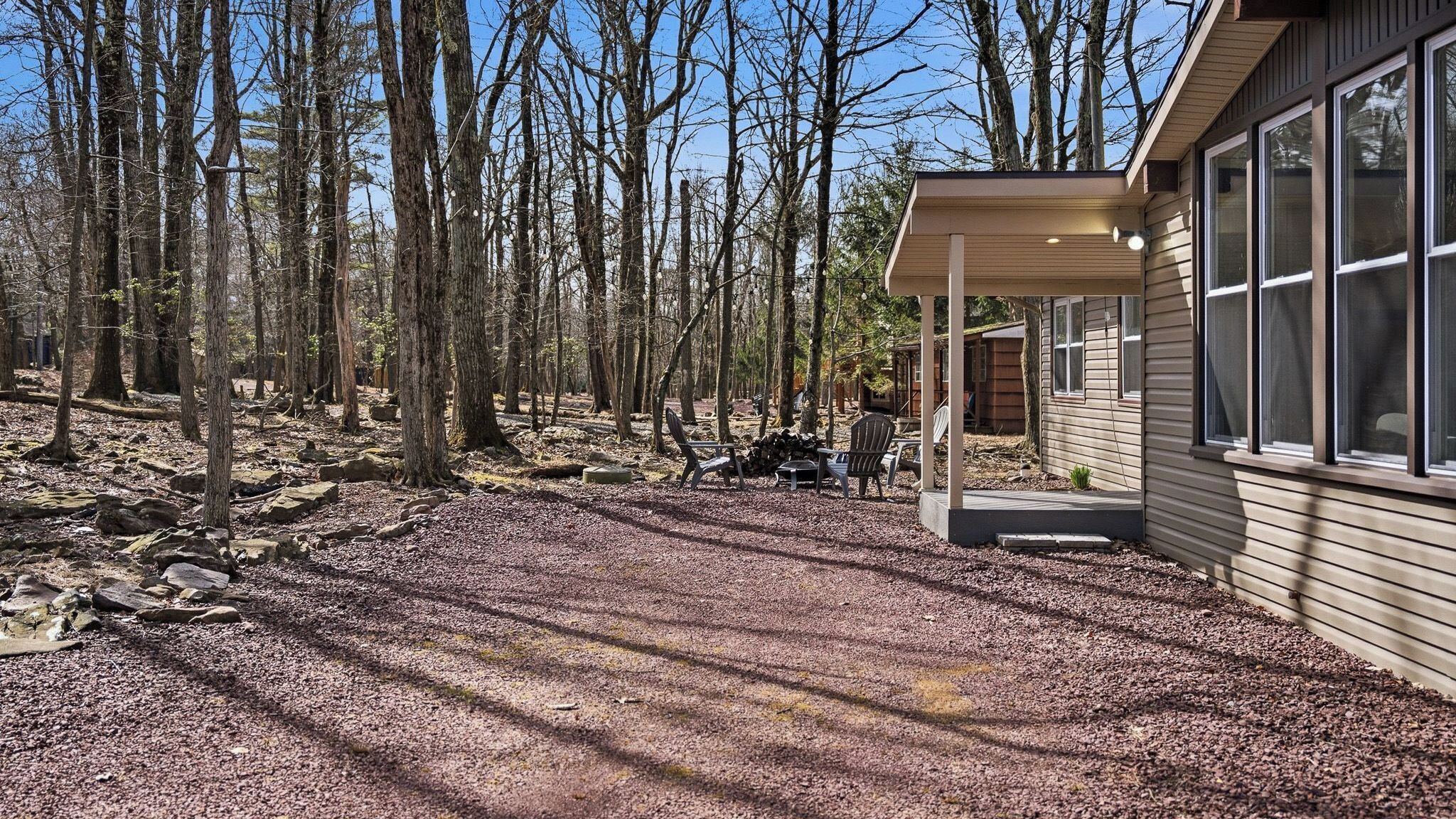 Une cabane dotée d’un porche abrité, entourée d’une zone boisée.