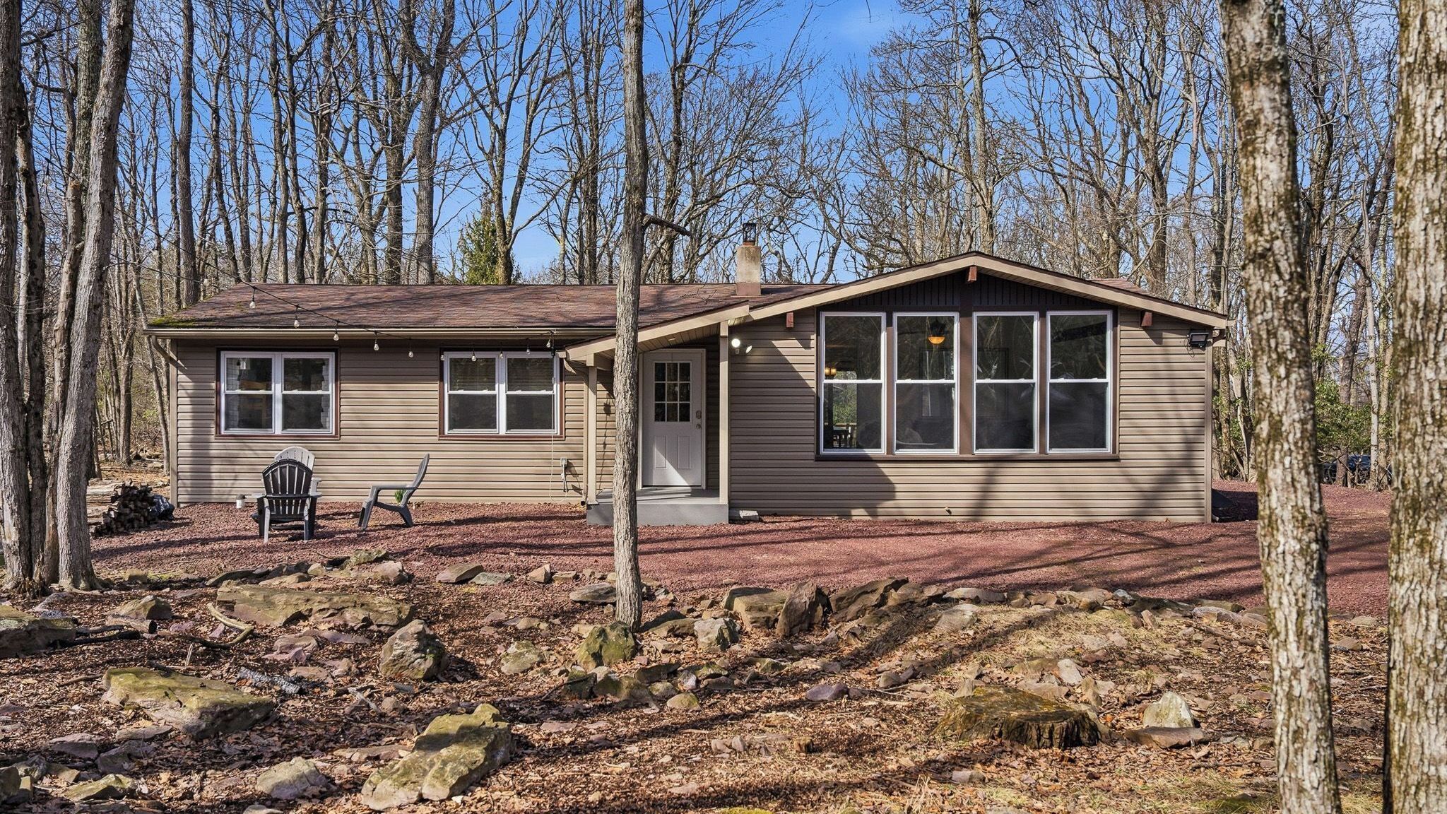 A single-story house with a front porch, a small deck, and a stone pathway leading to the entrance.