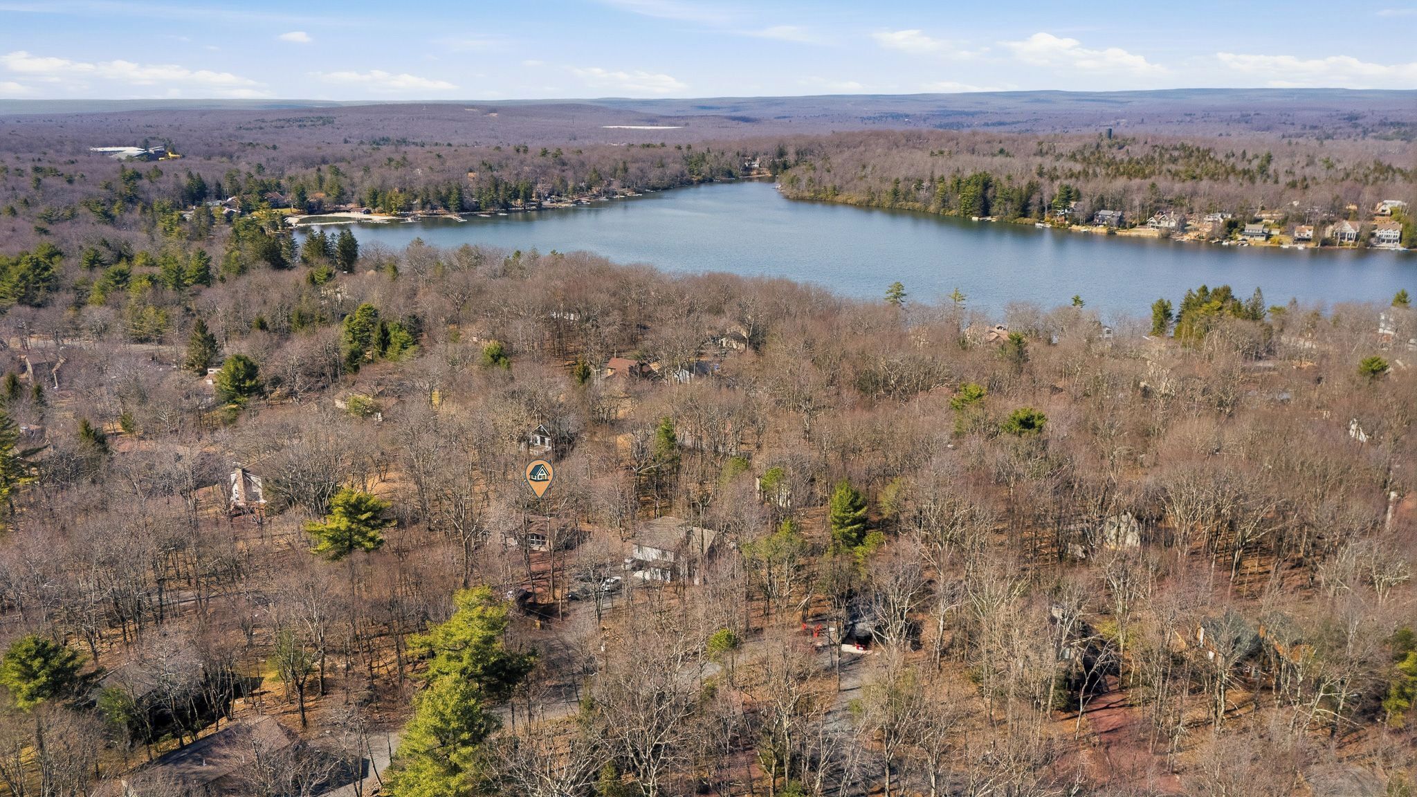 Un lac entouré de collines boisées, parsemées de quelques maisons.