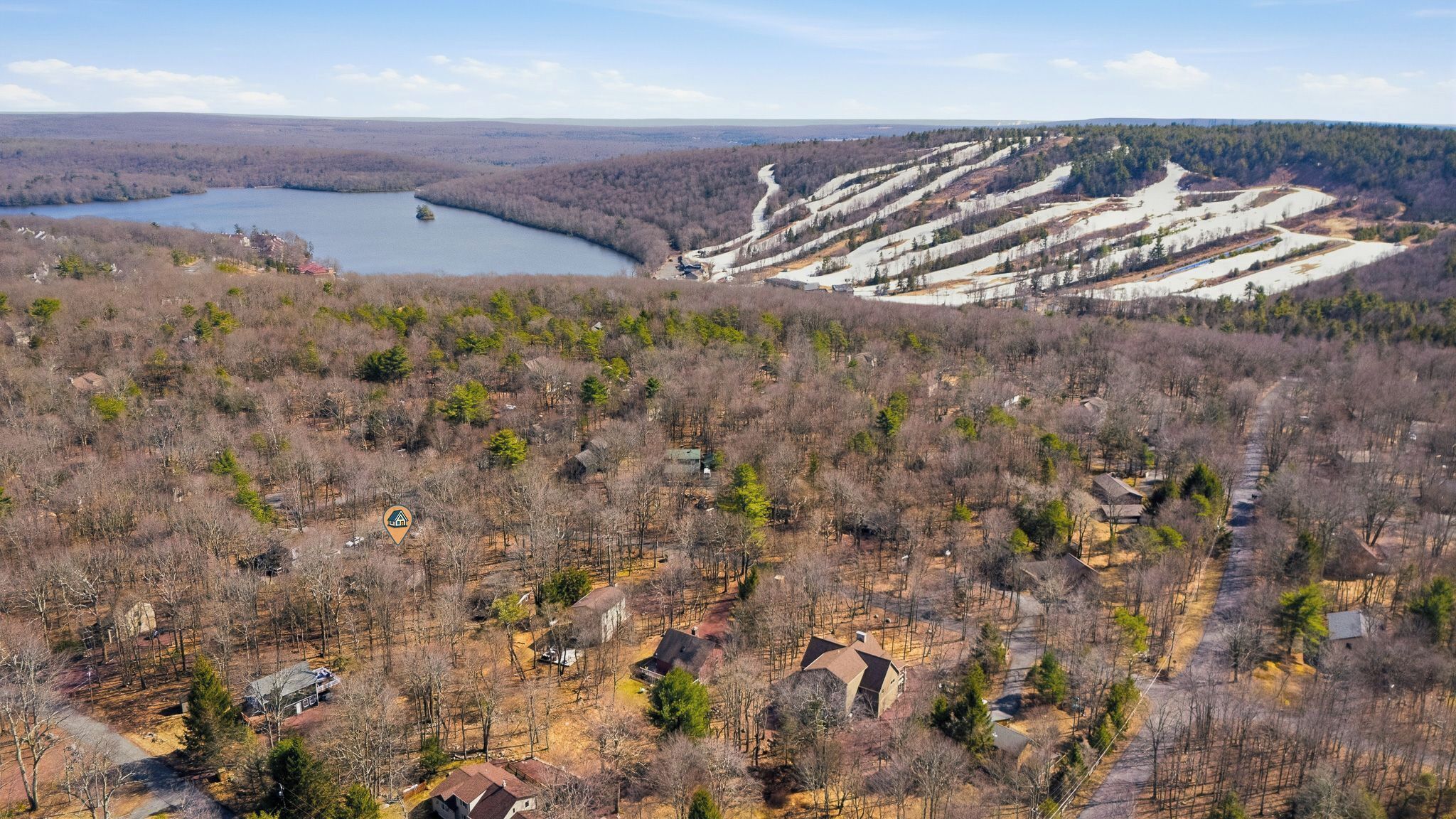 Una zona residencial con casas, un lago y una ladera boscosa.