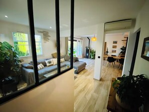 Ein modernes Wohnzimmer mit einer Couch, einem Essbereich mit Tisch und Stühlen und einer durchgehenden Tür erkennbaren Küche.