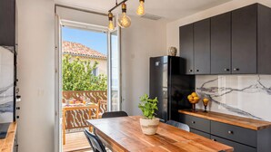 A kitchen with a wooden table, black cabinets, and a marble backsplash. - Casa Turturella – Vue mer et citadelle au cœur de Calvi (Calvi)