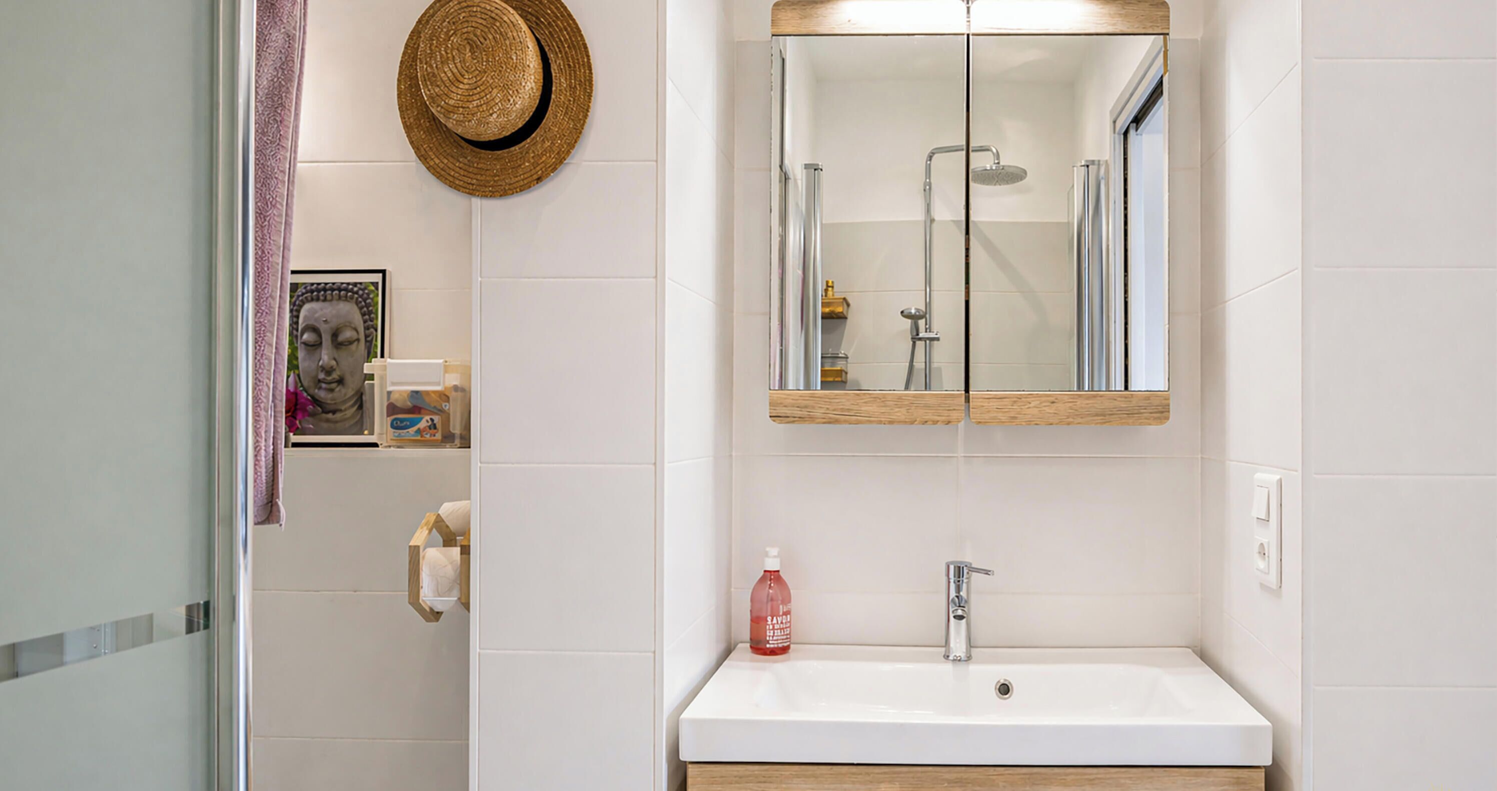 A bathroom with a white sink, a mirror, a shower, and a wooden vanity.