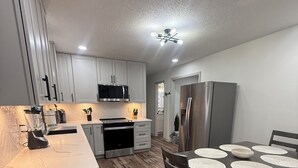 A modern kitchen with white cabinets, a stainless steel refrigerator, and a dining area with a table set for four. - Beautiful family house with 3-bedroom  in excellent Ringgold (Ringgold)