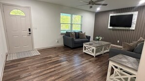 A living room with a sofa, coffee table, TV, and wooden flooring. - Beautiful family house with 3-bedroom  in excellent Ringgold (Ringgold)