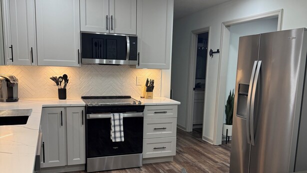 A modern kitchen with white cabinets, a stainless steel refrigerator, and a herringbone-patterned backsplash. - Beautiful family house with 3-bedroom  in excellent Ringgold (Ringgold)