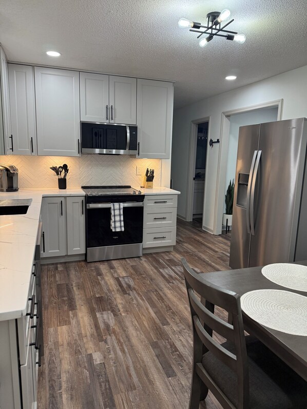 A modern kitchen with white cabinets, a stainless steel refrigerator, and a herringbone-patterned backsplash. - Beautiful family house with 3-bedroom in excellent Ringgold (Ringgold)