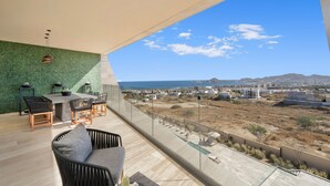 A balcony with a view of the sea and distant mountains, a dining area with chairs and a table, and a lounge area with a sofa. - Mistiq Views in Cabo San Lucas (Cabo San Lucas)