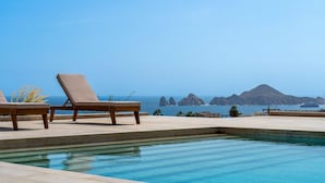 A pool with lounge chairs and a view of the ocean and mountains. - Mistiq Views in Cabo San Lucas (Cabo San Lucas)
