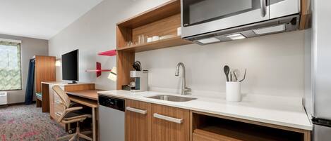 A modern kitchen with a microwave, sink, and wooden cabinets.