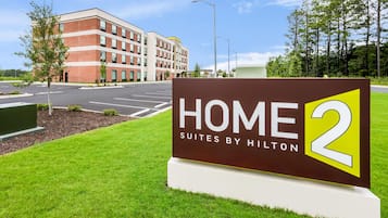 A sign for 'HOME 2 Suites by Hilton' with a modern building in the background.