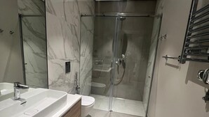 Uma casa de banho moderna com um espelho grande, duas lavatórios, cabine de duche e sanita.
