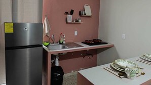 Eine kompakte Küche mit einem Edelstahlkühlschrank, einer Spüle und einer Arbeitsplatte mit Geschirrgestell.