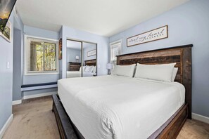 A bedroom with a large bed, a window with blinds, a mirror, and a sign on the wall. - Indoor Pool, Balcony & Fireplace , Mountain Views (Gatlinburg)