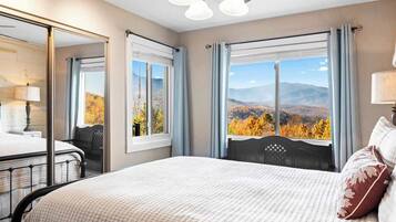 Ein Hotelzimmer mit Bett, Schreibtisch, Stuhl, Spiegel und Blick auf Herbstlaub.