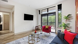 Ein modernes Wohnzimmer mit einer Couch, einem roten Sessel, einem Couchtisch und einem an der Wand befestigten Fernseher.