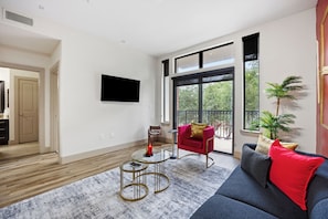 Ein modernes Wohnzimmer mit einer Couch, einem roten Sessel, einem Couchtisch und einem an der Wand befestigten Fernseher.