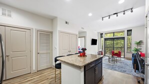 Eine moderne Küche mit Granit Arbeitsplatte, eingebauten Schränken und einem Essbereich mit einem roten Stuhl und einem kleinen Tisch.
