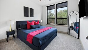 Ein Schlafzimmer mit einem Bett, einem Deckenventilator, einem Fenster und einem Spiegel.