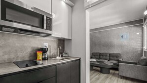Een moderne keuken met een ingebouwde magnetron, een koffieapparaat en een spoelbak.