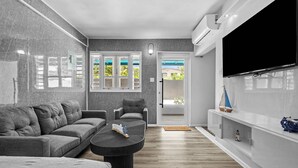 Een moderne woonkamer met een bank, fauteuil, salontafel en een flatscreen televisie.