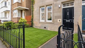 A residential building with a well-maintained lawn, a black front door, and a brick facade.