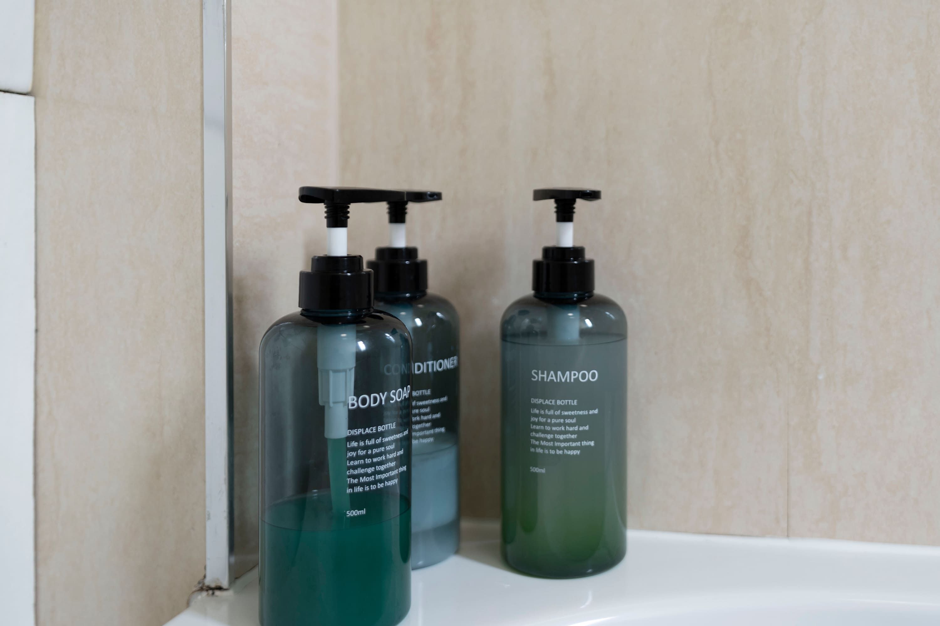 Three bottles of body soap and shampoo on a white surface.