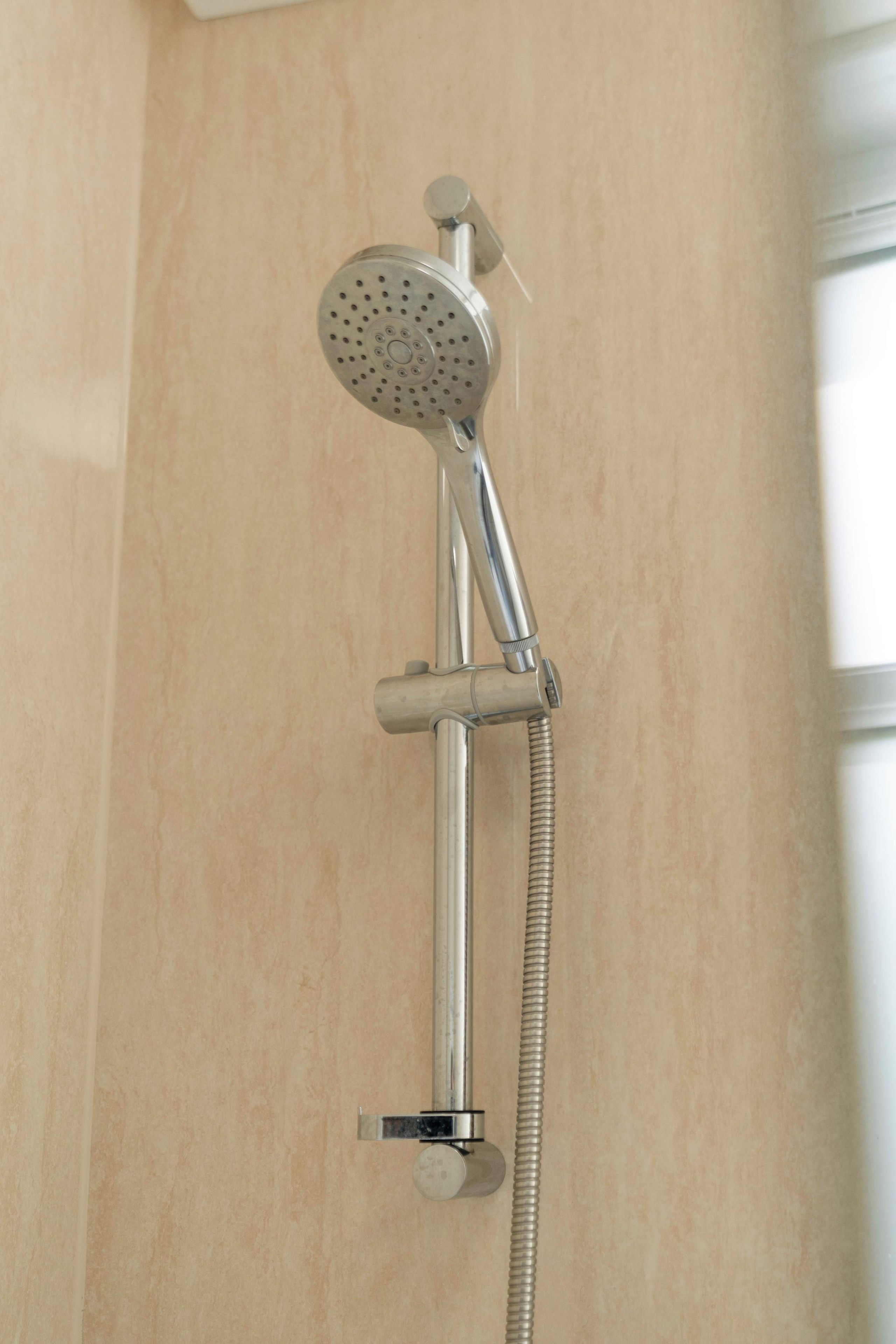 A showerhead with a flexible hose attached to a wall-mounted fixture.