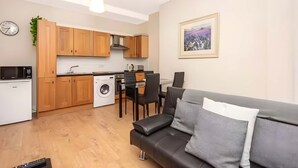 Un espacio habitable compacto con kitchenette, comedor y sofá.