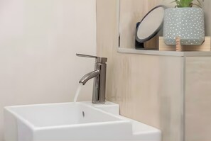 A modern bathroom with a white sink, chrome faucet, and a mirror above it.