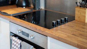 Een moderne keuken met een houten aanrecht, roestvrijstalen apparatuur en een geïntegreerde inductiekookplaat.