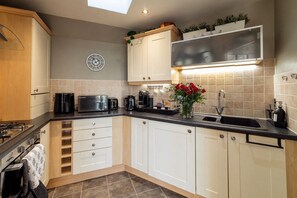 A modern kitchen with a gas stove, microwave, toaster, and coffee maker.