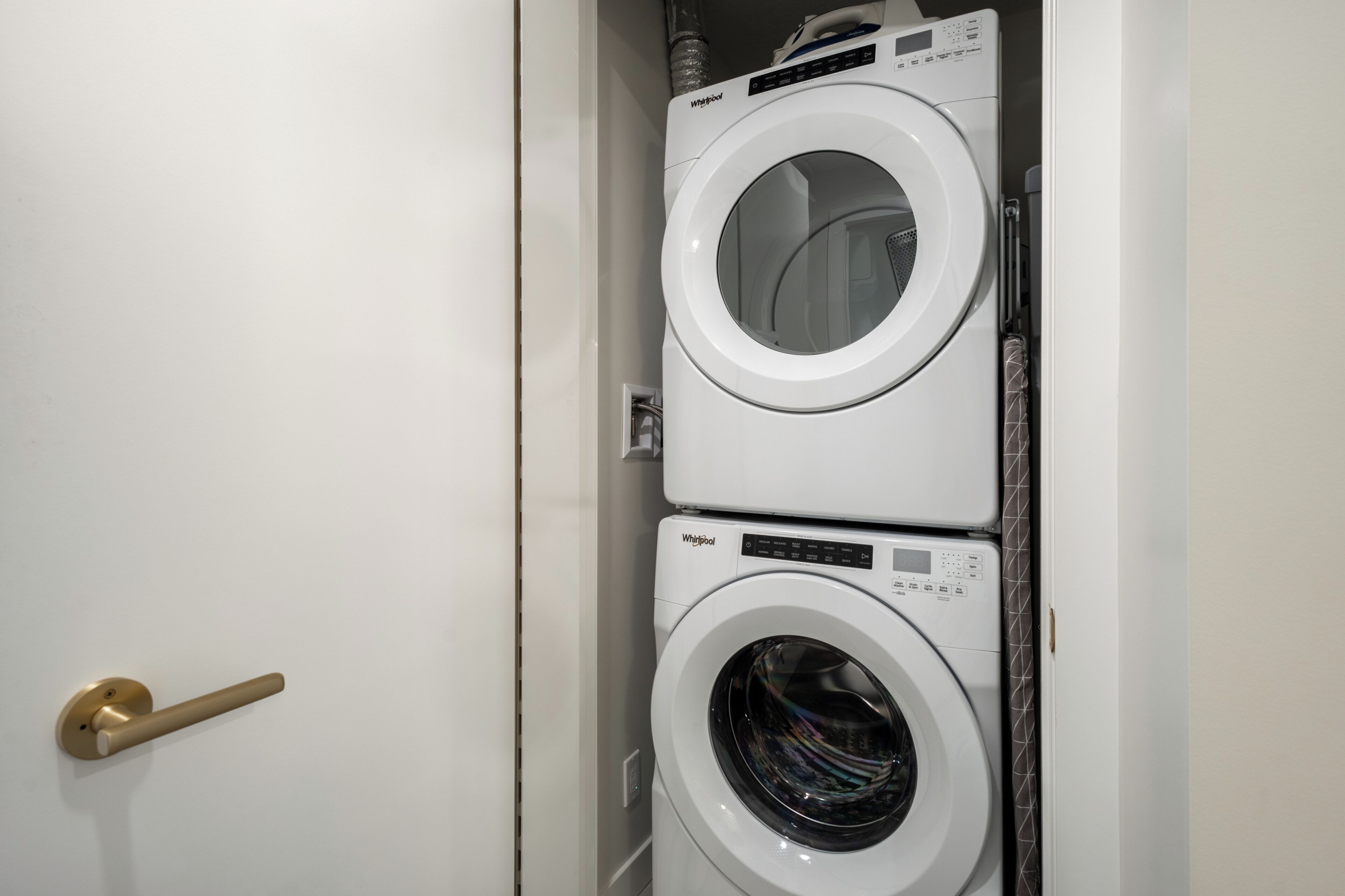 A stacked washer and dryer unit in a white utility room.