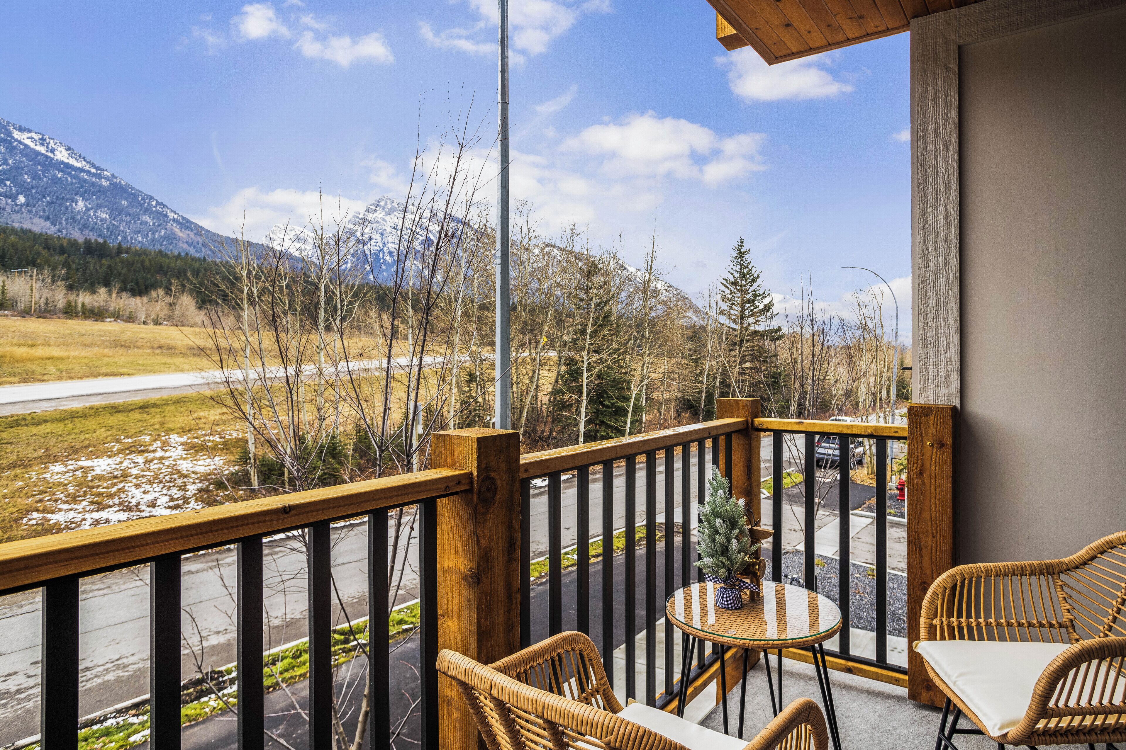 Ein Balkon mit Korbmöbeln, einem kleinen Tisch und einem Blumentopf.