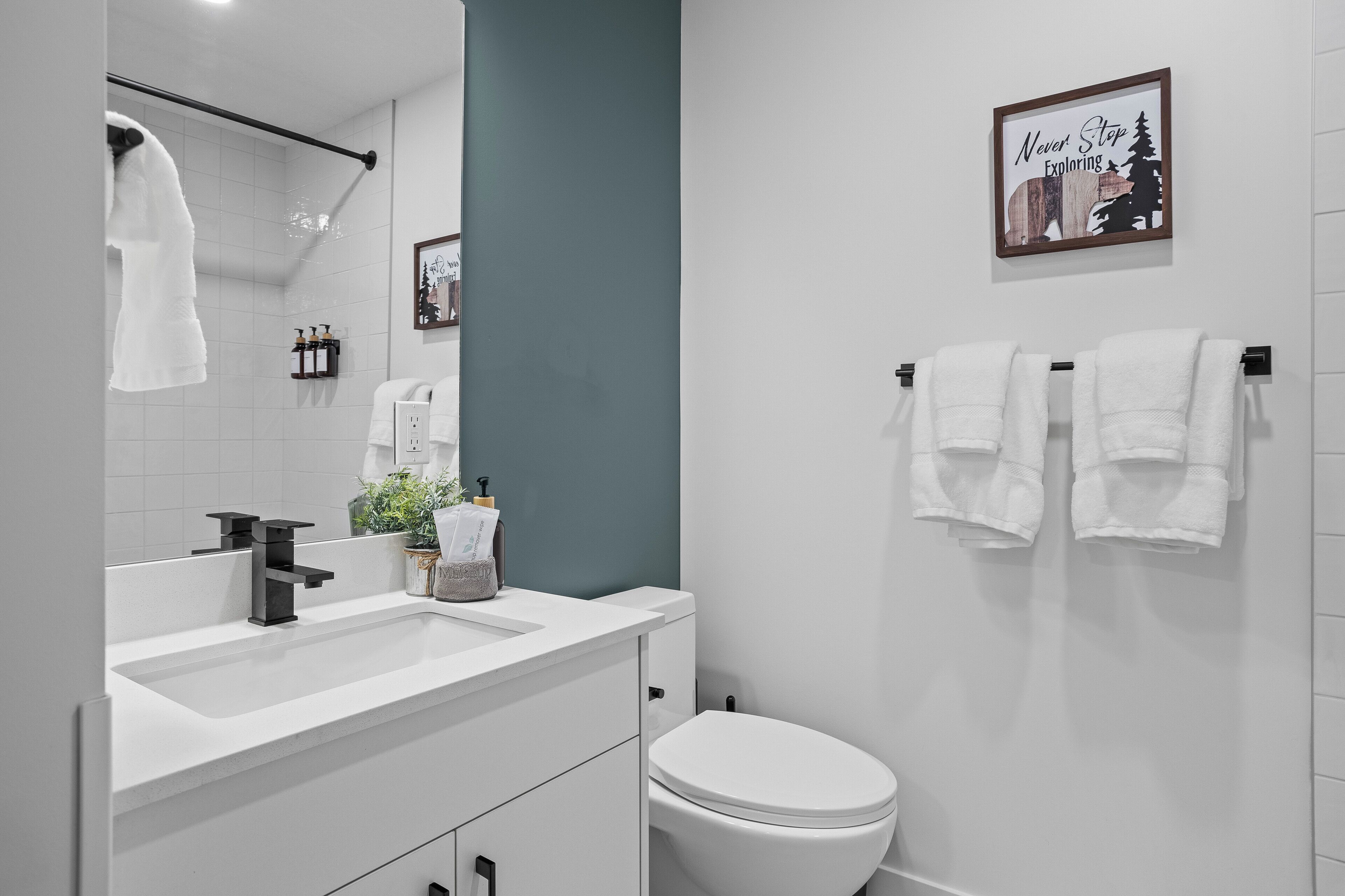 A modern bathroom with a white sink, a toilet, and a towel rack.