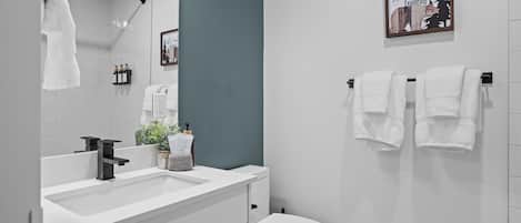 A modern bathroom with a white sink, a toilet, and a towel rack.