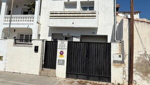 A two-story building with a gated entrance, a balcony, and a sign indicating the property number.