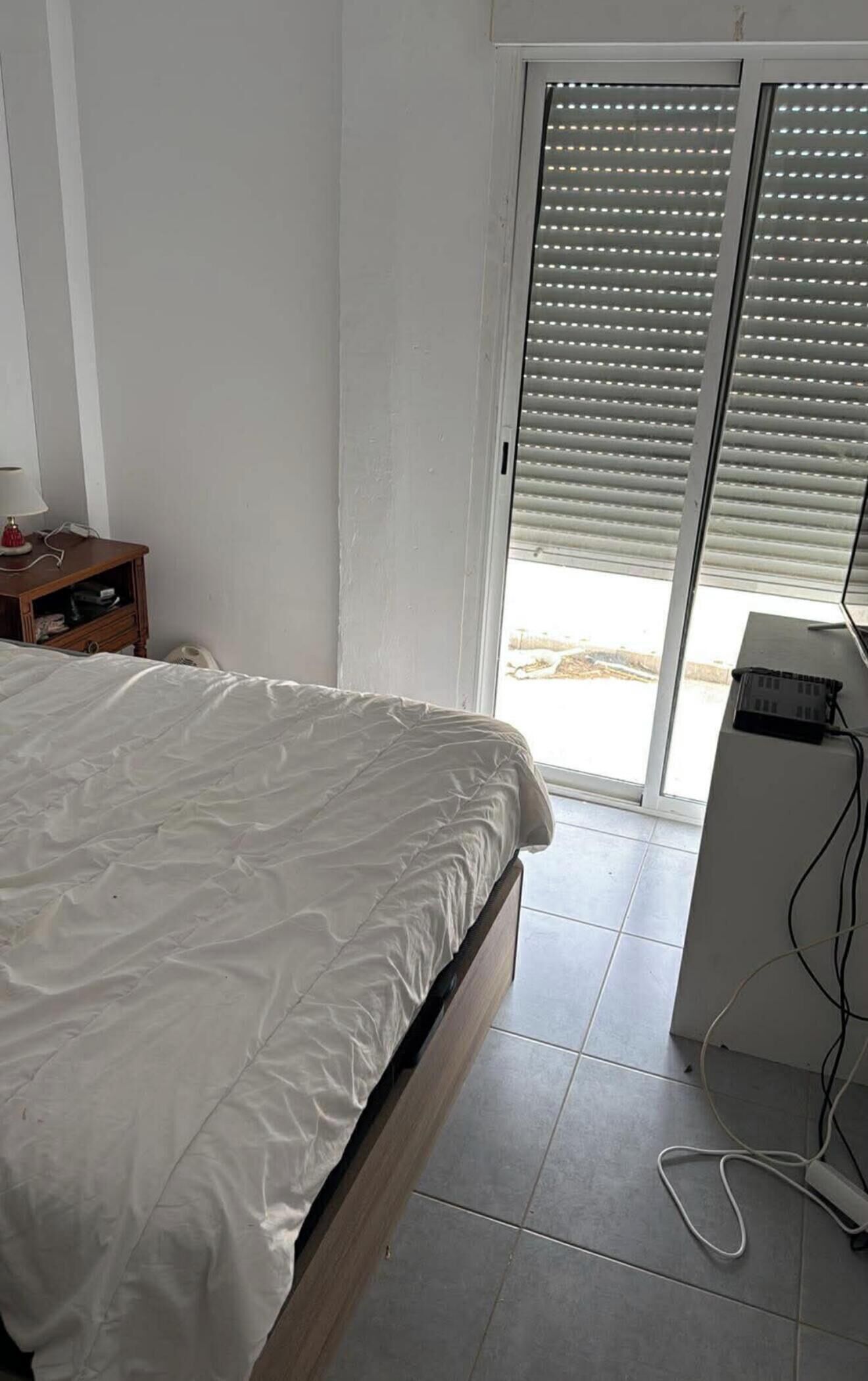 Ein Schlafzimmer mit einem Bett, einem Schreibtisch und einem Fenster mit Jalousien.