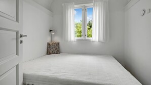 A room with a bed, a window with curtains, a wall-mounted light, and a door. - 1 bedroom gorgeous home in Gilleleje (Gilleleje)