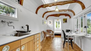 A modern kitchen with wooden cabinets, a built-in sink, and a dining area with chairs and a table. - 1 bedroom gorgeous home in Gilleleje (Gilleleje)