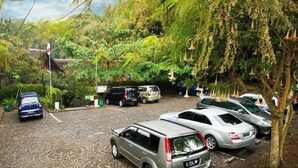 A parking area with several cars, surrounded by lush greenery and trees. - Kampung Sampireun Resort And Spa (Samarang)