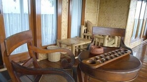 A wooden chair, a small table with a woven basket, and a wooden tray with a bowl. - Kampung Sampireun Resort And Spa (Samarang)
