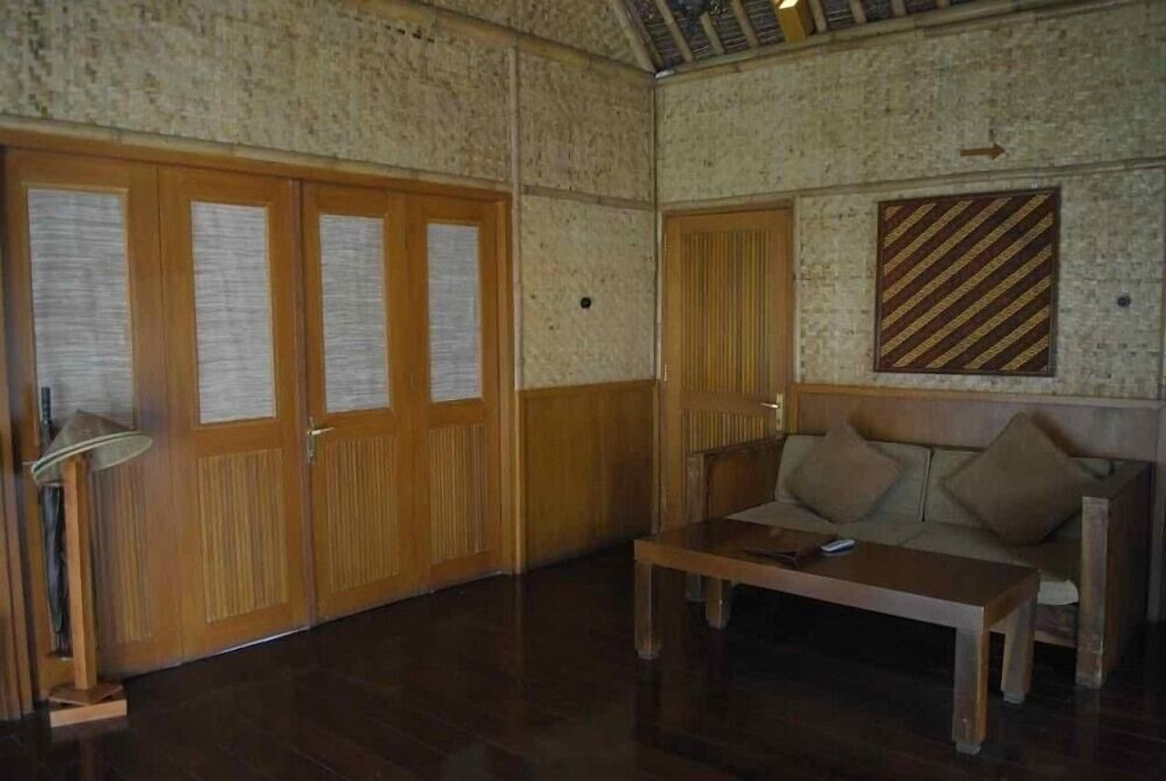 A room with wooden doors, a sofa, a table, and a lamp.